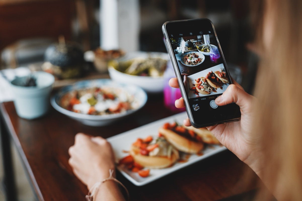 Une personne photographie son plat au restaurant avec son téléphone